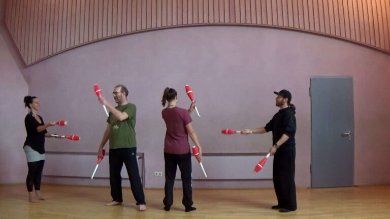 Four people juggling red and white clubs in a spacious room. - Passing Zone