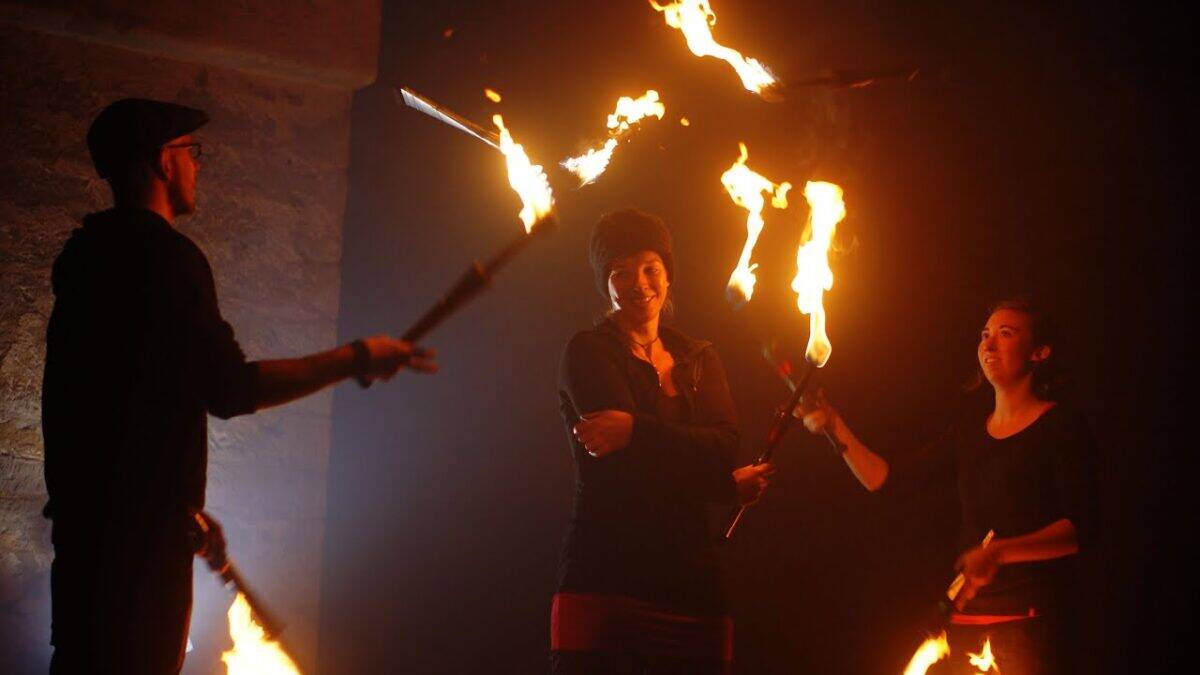 Fire performers juggling flaming clubs in a dark space. Club on Fire. - Passing Zone