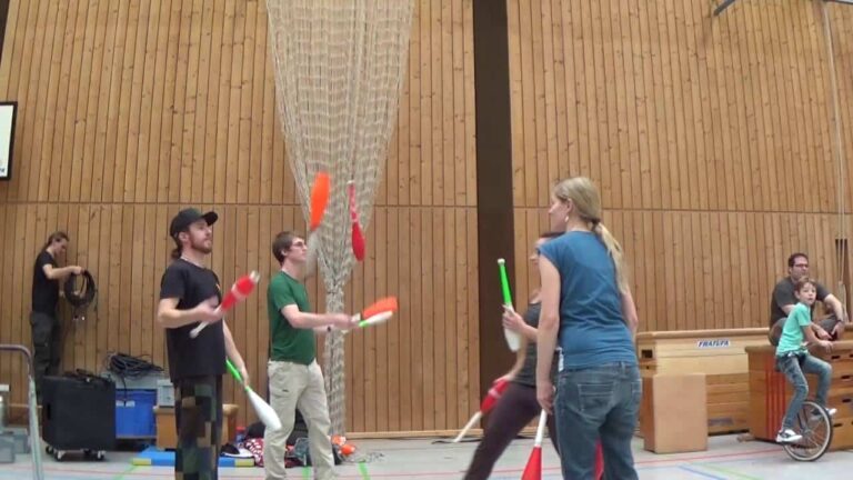 Group of people juggling colorful clubs in a gymnasium. - Passing Zone