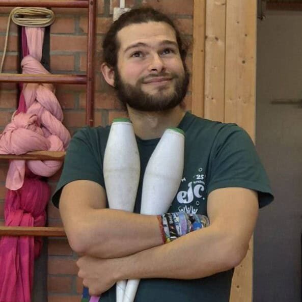 Man with beard holding juggling clubs, smiling. - Passing Zone