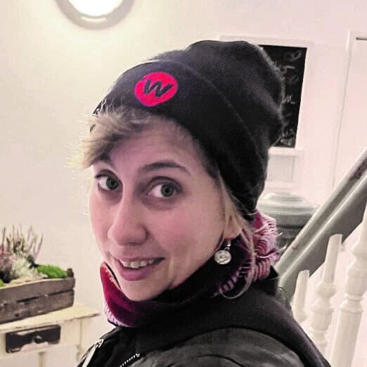 Woman in beanie with "W" logo. Indoor portrait. - Passing Zone